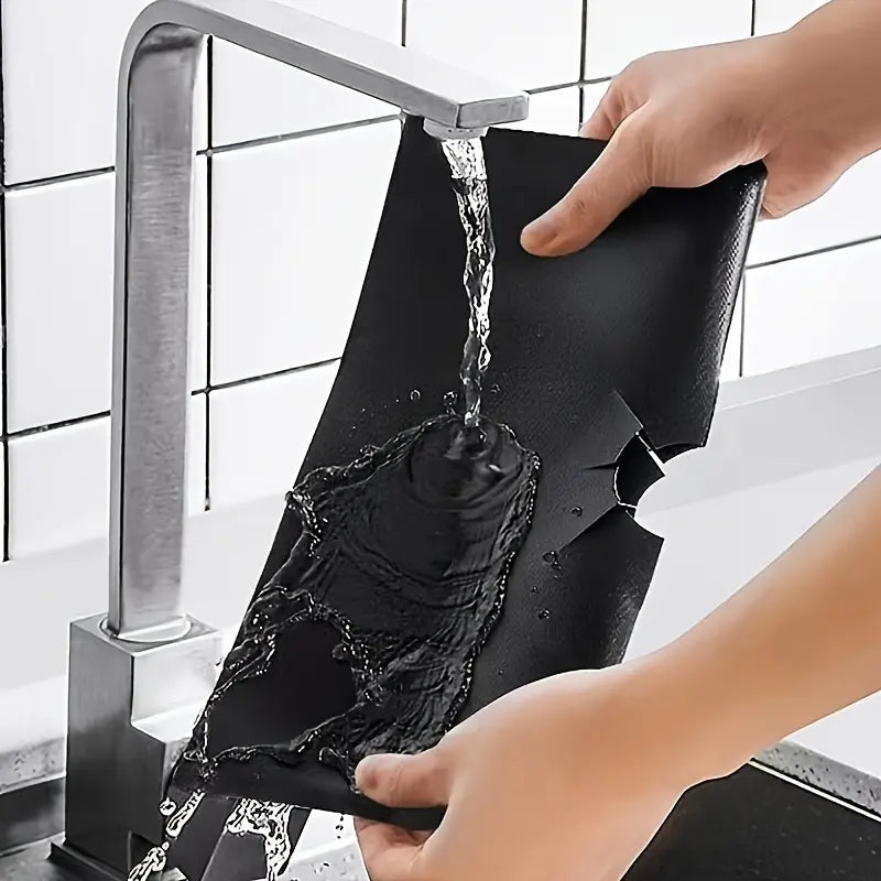 Reusable stove liner being rinsed clean